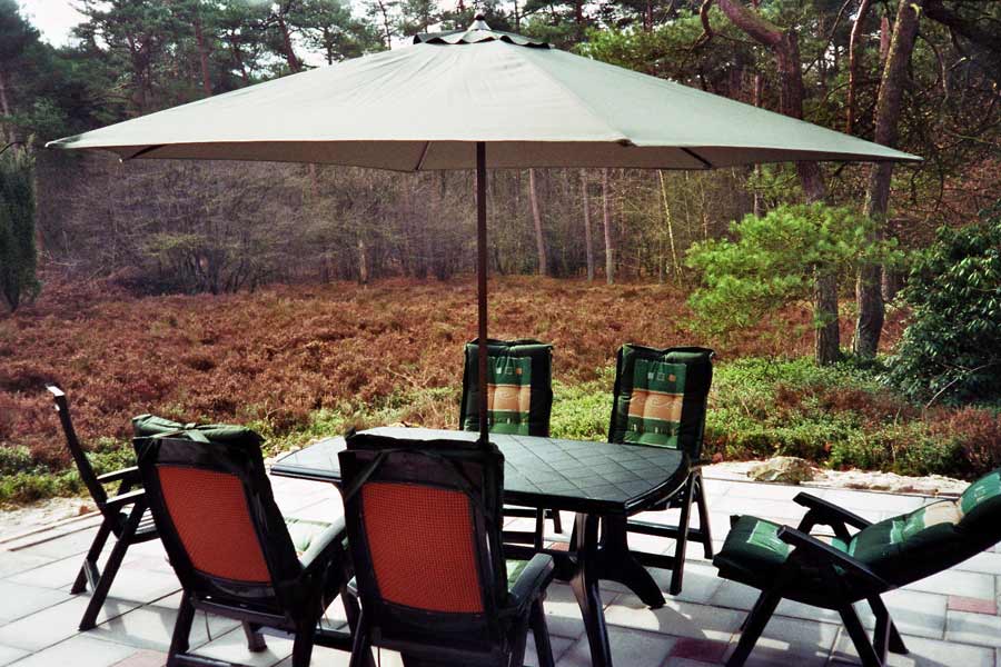 De Schuilplaats: overdekt terras op het zuiden, met uitzicht op de heide (die bloeit in agustus / september) en een heel grote rhododendron (die in mei / juni prachtig bloeit).